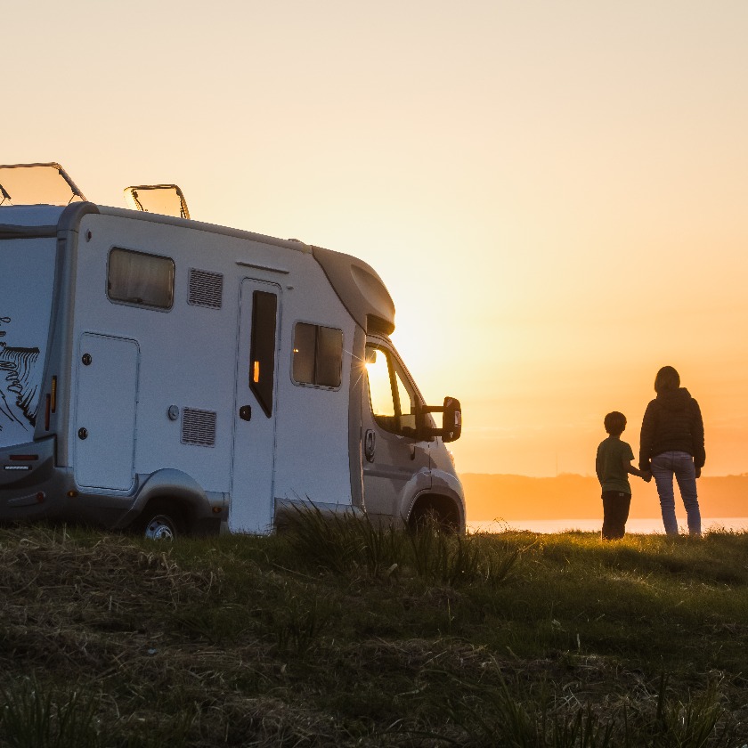 Mother and son watching the sunset with their motor home at the edge of the sea jpg