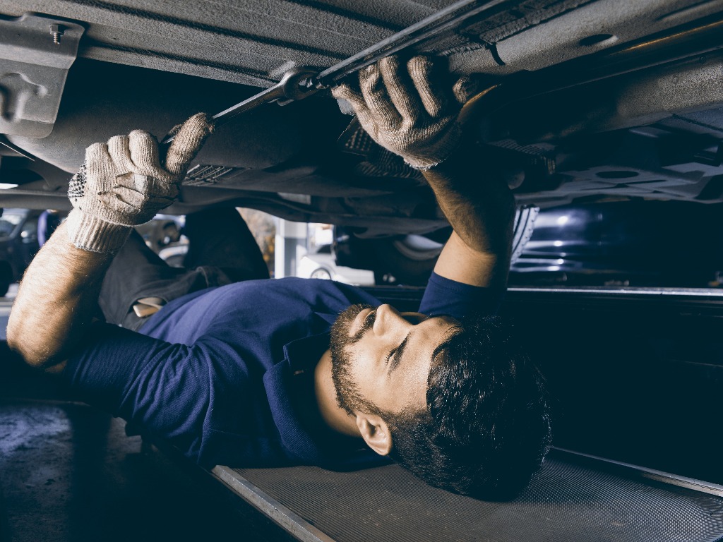 Mechatroniker bei Unterboden Reparatur am Auto